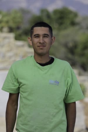 A man in a green shirt standing in front of a building.