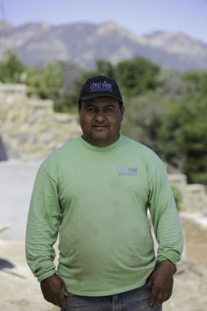 A man in a green shirt standing in front of a building.