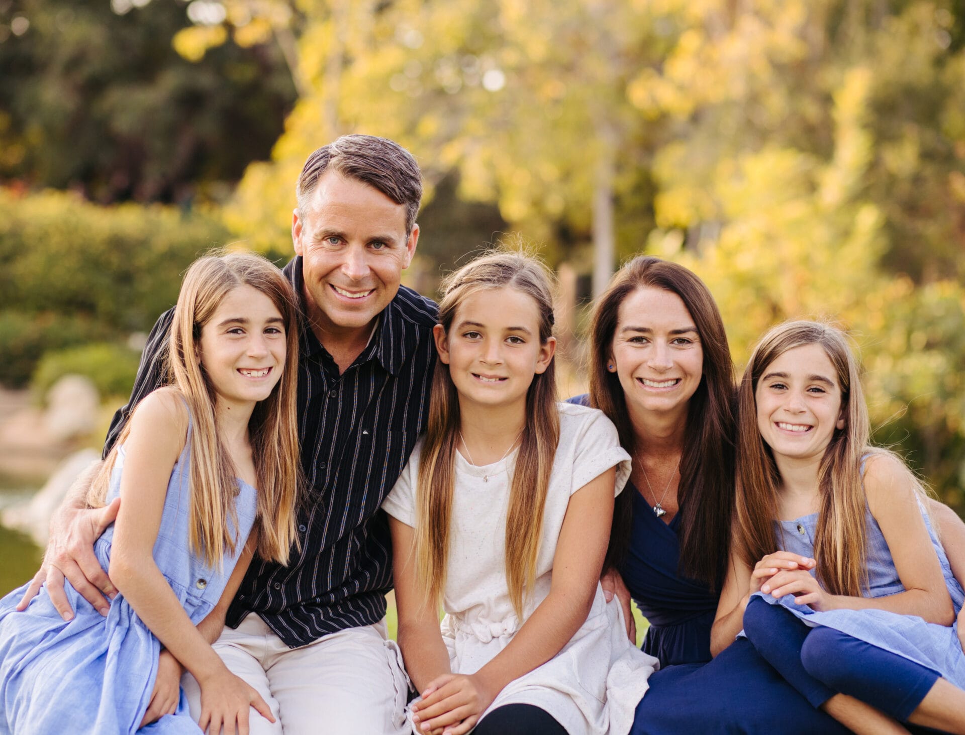 A family posing for a photo in a park with Santa Barbra Landscaping in the background.